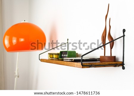 mid century vintage book shelf  danish design spaceage 50s 60s modern hanging on the wall rack with transparent acrylic bracket and orange arc lamp isolated on white background HIGH RESOLUTION Studio 