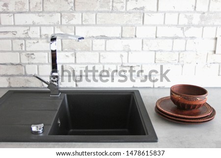 black ceramic sink with mixer on a background of white bricks with clay bowls, Scandinavian style