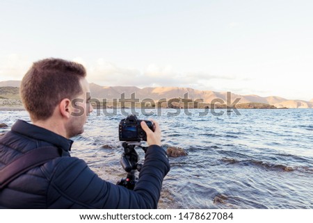 Young man making landscape photos at the sea. photographer profession.