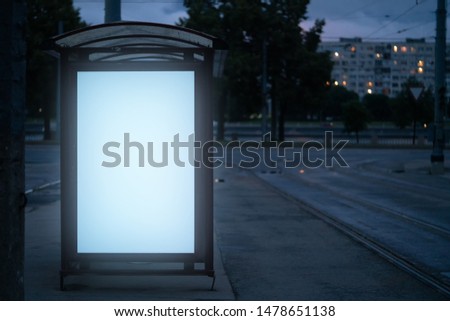 billboard at the bus stop outdoor ad.bus shelter with white field glowing at night in the city mockup advertisement.