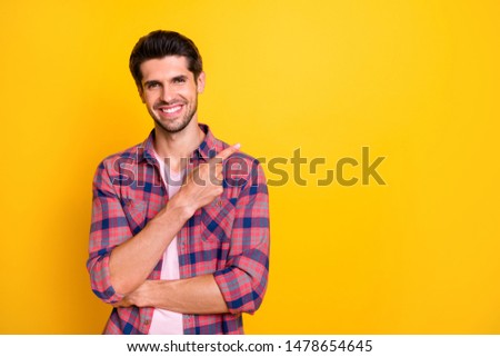 Photo of smiling cheerful person advertising you something having to be instead of emptiness while isolated with yellow background
