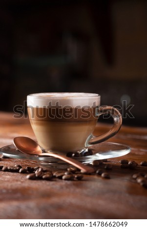 Cup of coffe with milk on a dark background. Hot latte or Cappuccino prepared with milk on a wooden table