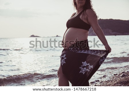 Unrecognizable pregnant woman standing on the beach