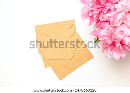 Minimal flatlay style composition, concept of wedding and marriage. Beauty or fashion blog banner mockup. Handmade envelopes and a bouquet of peonies on a light gray background