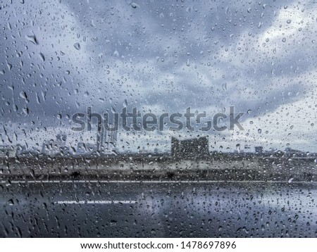 Rain drops stuck the car window area on blurred Building background, Blurred landscape in Bangkok at Thailand in rainy day, on expressway