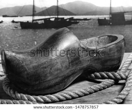 Old Wooden shoe on dock pier in front of sail boats. 
