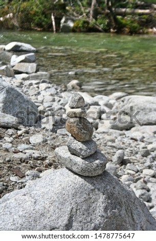 Stones in the mountains arranged in a pyramid. Stones stacked on each other in the background of nature, relaxation and meditation. In the background a mountain stream.