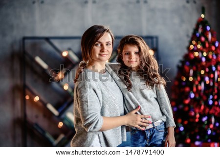 Merry Christmas and Happy Holidays! Cheerful mom and her cute daughter girl. Parent and little child having fun near Christmas tree indoors. Loving family with presents in room.