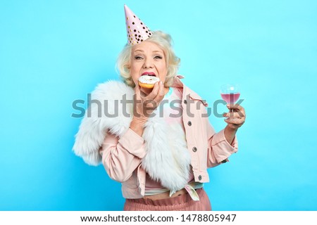 glamour crazy funny grandmother in stylish clothes celebrating her anniversary alone. close up portrait. isolated blue background. studio shot