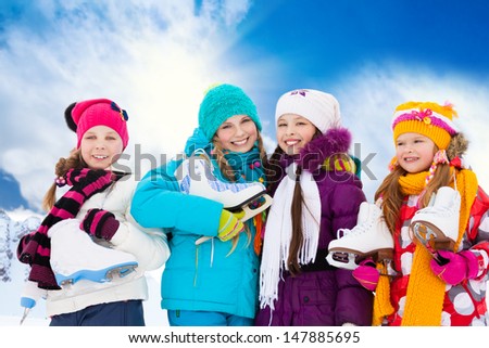 Close portrait of group of four happy smiling Caucasian girls friends standing outside with ice-skates