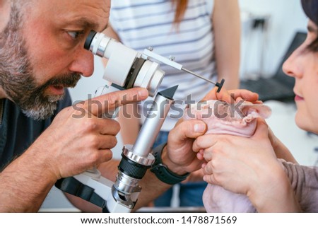 Male veterinarian and nurse examining with magnifying glass and light a blind cat for laser eye surgery.