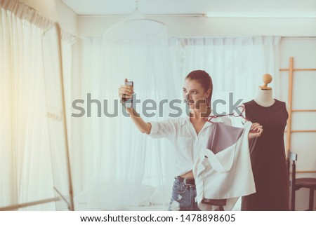 Young beautiful woman standing in clothes shop and choosing dresses,Happy and smiling,Fashion and lifestyle concept