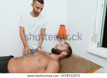 Massage is essential for the recovery of the body. A man lies on a table while a therapist massages him