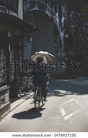 Japanese Woman Riding Bike with Umbrella 