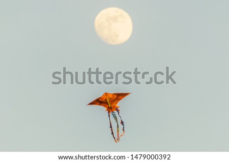 A single kite is flying under the full moon. Outdoor landscape picture of the clear twilight night, dark blue sky taken at Lam Vien square, Dalat, Vietnam