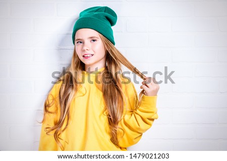 A close-up of a pretty girl in bright casual clothes posing in studio. Beauty, fashion for kids.