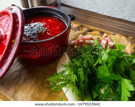 Tasty beetroot soup in pot on wooden surface. Traditional ukrainian russian soup borscht with greens, onion, parsley, dill, lard. Side view