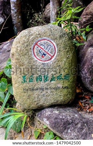 No Smoking sign on the rock, with Chinese and English wording. 