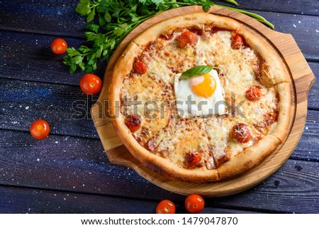pizza with cherry tomatoes, suri and egg on a background of a space board