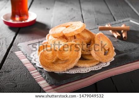 Homemade Eid and Ramadan Turkish Dates Sweets cookies puff pastry with pink napkin and Arabian tea on black wooden background 