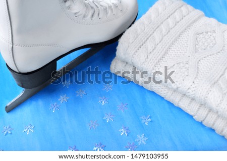 White figure skate and knitted scarf against the blue background