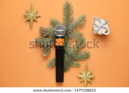 Modern microphone with Christmas decor on color background