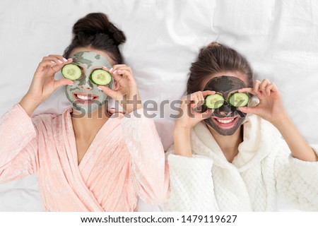 Young friends with facial masks having fun on bed at pamper party, top view Royalty-Free Stock Photo #1479119627