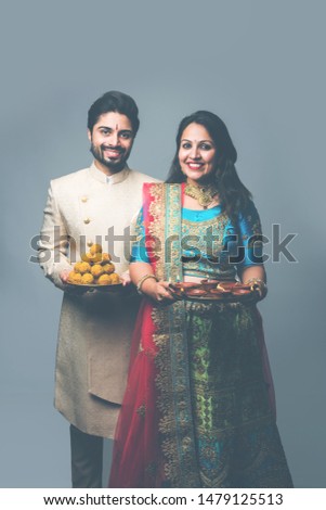Cute couple holding thali having diya and sweet laddu food