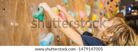 little boy climbing a rock wall in special boots. indoor BANNER, LONG FORMAT