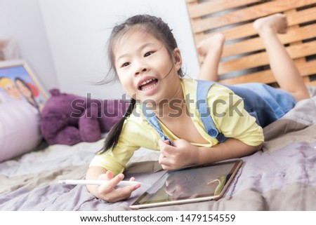 Smiling Asian school child girl drawing on tblet computer by hand education concept