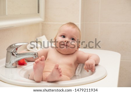 A happy little girl is bathing in the hotel sink.