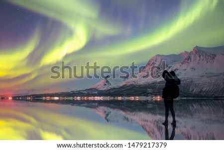 Silhouette of female photographer take a photograph at aurora borealis