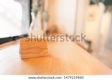 Wooden tag stand label on wood table. Modern minimal white room concept blur background.