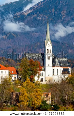 View of town Bled, Slovenia with church tower. Autumn colorful trees background