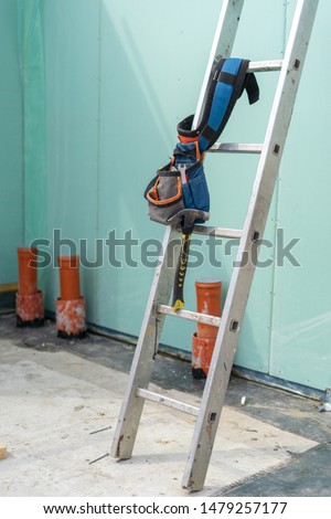Construction new and modern modular house from composite sip panels. Vertical photo of tool belt with instrument on metal ladder by the wall