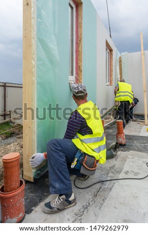 Vertical photo of process construction new and modern modular house from composite sip panels. Builder man in special uniform wear working on building development industry of energy efficient property