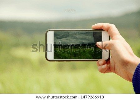 The hands of the young traveler are taking pictures of the scenery with mobile phones