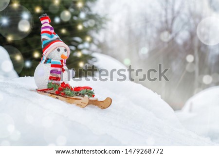 Snowman slides downhill on a sled - winter and Christmas fun concept, place for text, copy space