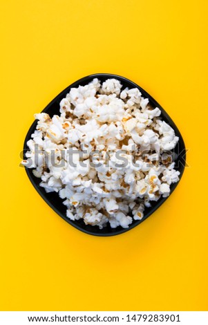 Top view of air tasty popcorn on yellow background. Snack for a movie, an idea for a meal. Close-up, top view. Copy space for text.