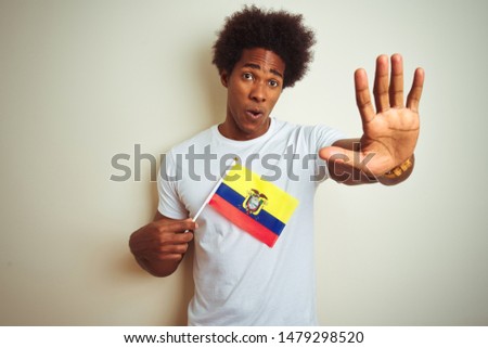 Afro american man holding Colombia Colombian flag standing over isolated white background with open hand doing stop sign with serious and confident expression, defense gesture