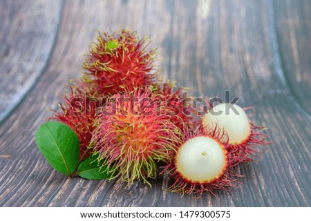  Fresh Rambutan on wooden table background. rambutans sweet fruit with green leaves on  wooden background.