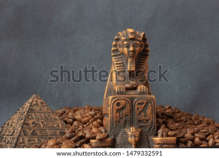 
sphinx figurine and pyramid figurine stand on coffee beans