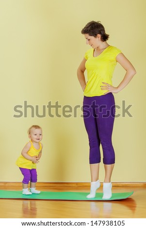 Mother do phisical exercises with her daughter at home