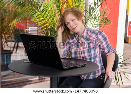 young girl looks thoughtfully at a laptop screen 