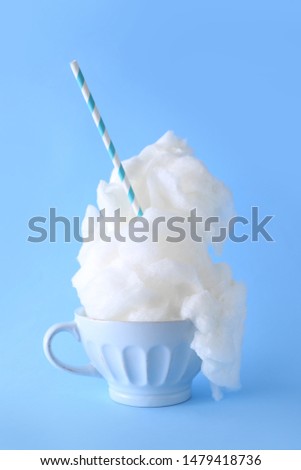 Cup with tasty cotton candy on color background