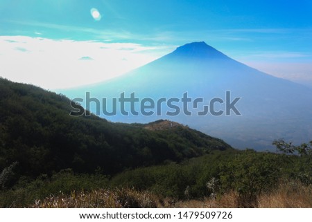 view of Mount Slamet from the viewpoint of Mount Sindoro accompanied by clouds and blue sky