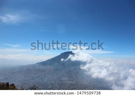 view of Mount Slamet from the viewpoint of Mount Sindoro accompanied by clouds and blue sky