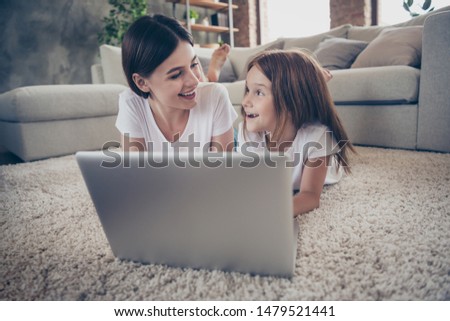 Close up photo of cute student little kid lying on floor watch netbook laughing wearing white t-shirt indoors Royalty-Free Stock Photo #1479521441