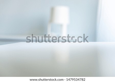White interior bokeh background with copyspace on white cupboard with reflection of the room. Gray empty room studio used for background