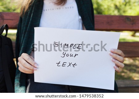 Beauty girl holding poster with sign Simple your text, background of summer green park, outdoors (banner for your message)